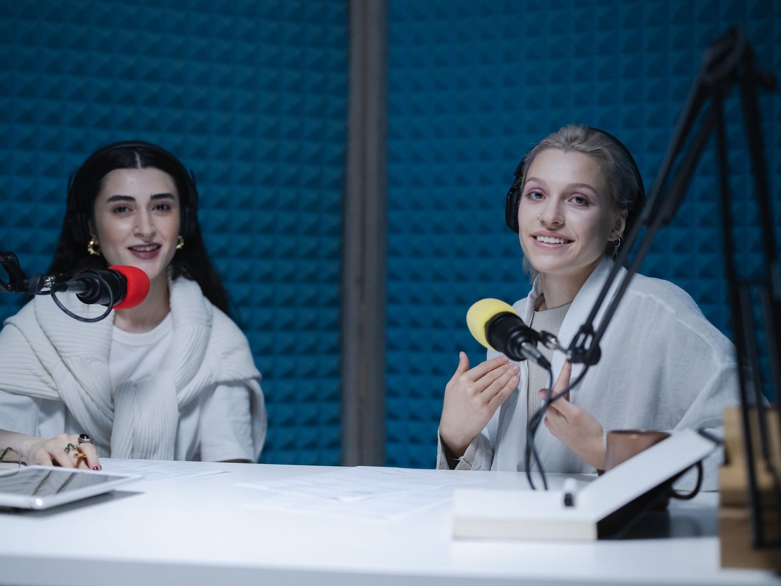 Two people recording a podcast using professional microphones and headphones in a studio